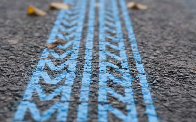 Blue tyre-track markings on asphalt drawn from the MINI logo