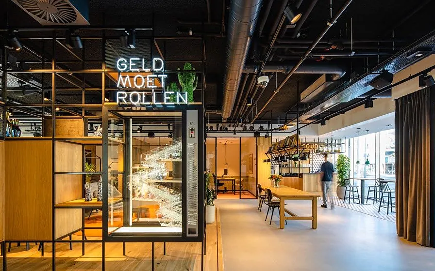 Bar and long table under a black steel frame with a neon sign