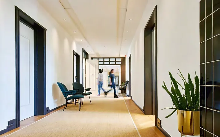 White corridor with timber floor and teal lounge chairs
