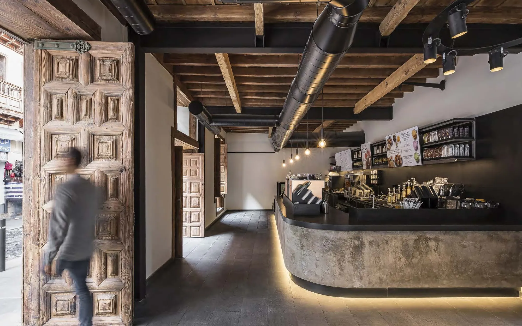 Concrete bar under original timber beams, with a carved door in the foreground
