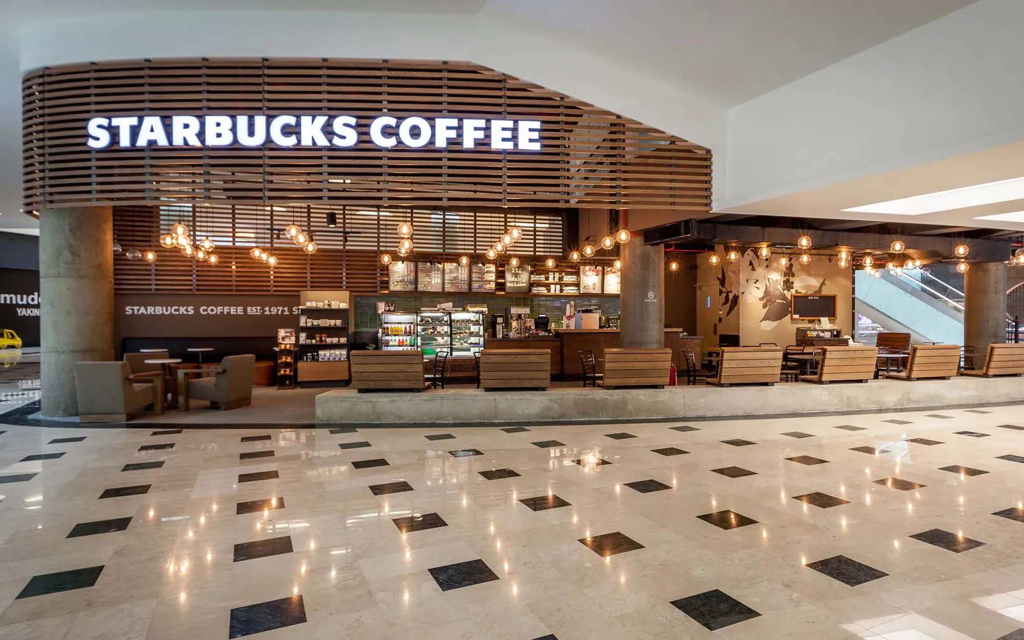 Open storefront under a slatted timber band in a marble-floored mall